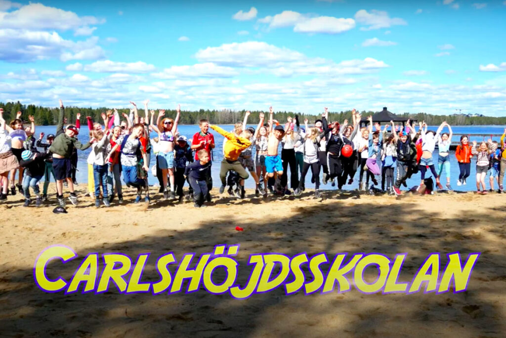 Elever som står på en lång rad på en strand och hoppar upp i luften.