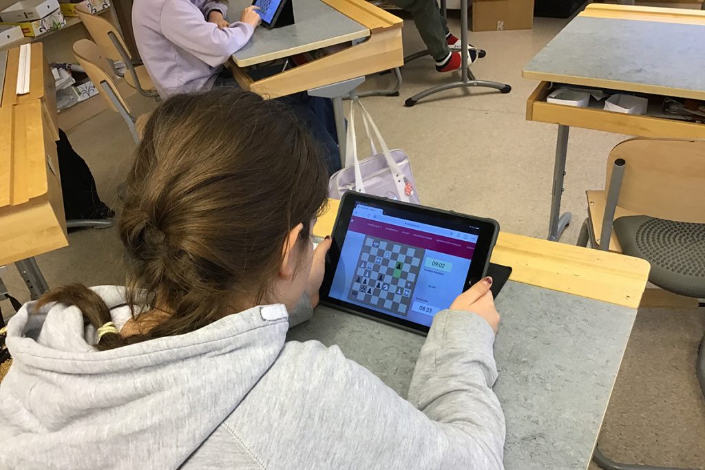 Emira sitter framför läsplattan och sitt schackparti.