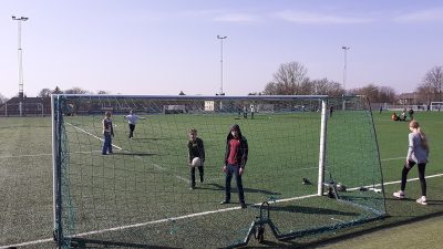 En stor fotbollsplan och några elever som leker på den.